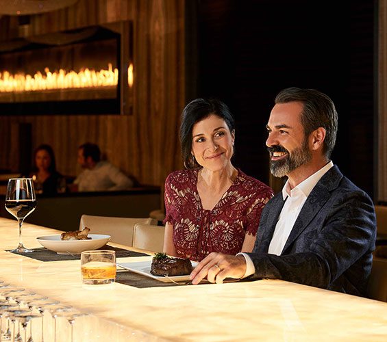 A man and woman sitting at the 630 Park Steakhouse Bar
