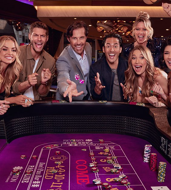 Group of excited friends standing on one side of a Craps Table